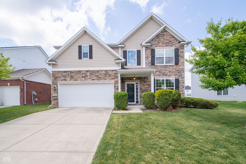 8710 N Aspen Way, Mccordsville, IN 46055 - view of front of home with concrete driveway, stone siding, a front yard, and an attached garage