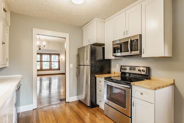 595 W Poplar St, Zionsville, IN 46077 - kitchen featuring appliances with stainless steel finishes, light wood-style floors, butcher block counters, baseboards, and a textured ceiling