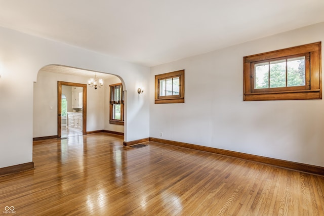595 W Poplar St, Zionsville, IN 46077 - unfurnished room featuring arched walkways, a chandelier, baseboards, and hardwood / wood-style floors