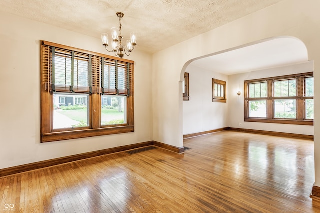 595 W Poplar St, Zionsville, IN 46077 - unfurnished room with arched walkways, light wood-style flooring, baseboards, a chandelier, and a textured ceiling