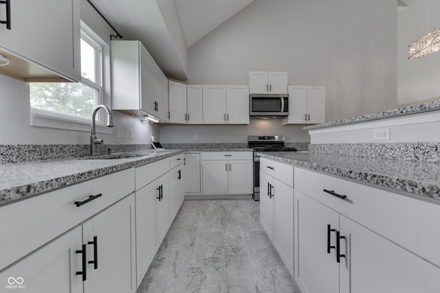 9317 E 36th Pl, Indianapolis, IN 46235 - kitchen with appliances with stainless steel finishes, light marble finish floors, vaulted ceiling, a sink, and white cabinets