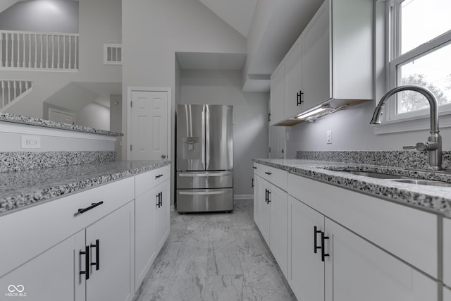 9317 E 36th Pl, Indianapolis, IN 46235 - kitchen featuring stainless steel refrigerator with ice dispenser, a sink, light marble finish flooring, light stone countertops, and vaulted ceiling