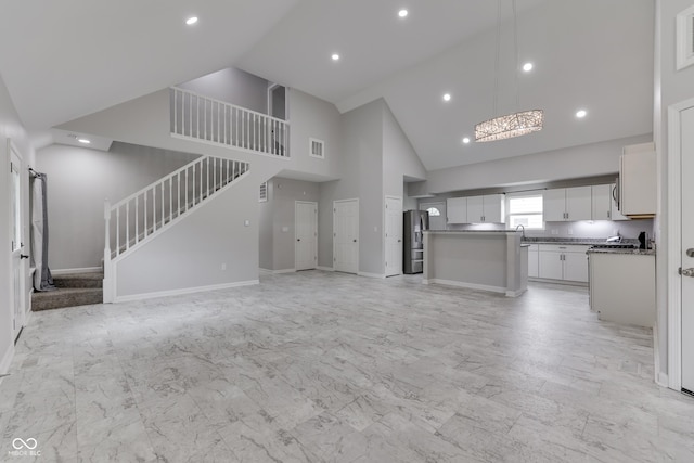 9317 E 36th Pl, Indianapolis, IN 46235 - unfurnished living room with high vaulted ceiling, stairway, light marble finish flooring, baseboards, and recessed lighting