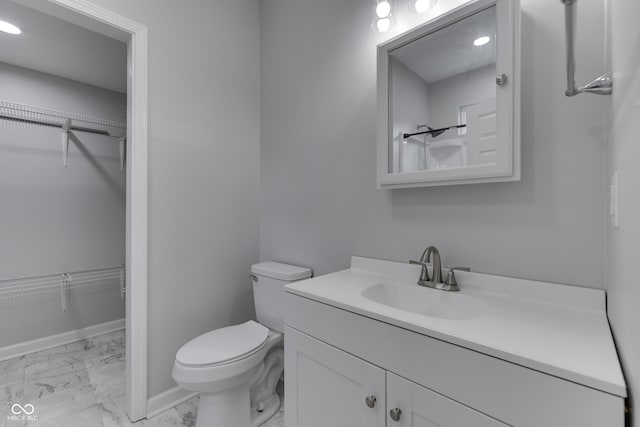9317 E 36th Pl, Indianapolis, IN 46235 - bathroom featuring marble look tile flooring, vanity, toilet, a spacious closet, and baseboards