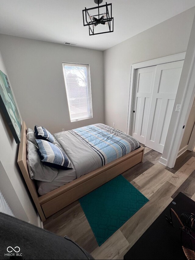 811 E Minnesota St, Indianapolis, IN 46203 - bedroom featuring wood finished floors, a closet, and a chandelier