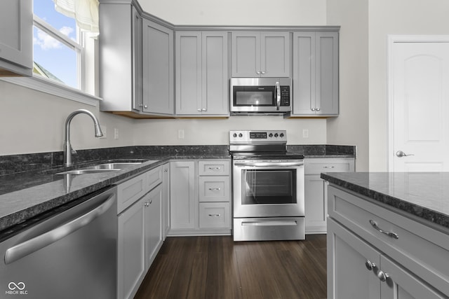 11815 Adair Pl, Indianapolis, IN 46229 - kitchen featuring appliances with stainless steel finishes, gray cabinetry, a sink, dark stone counters, and dark wood-type flooring