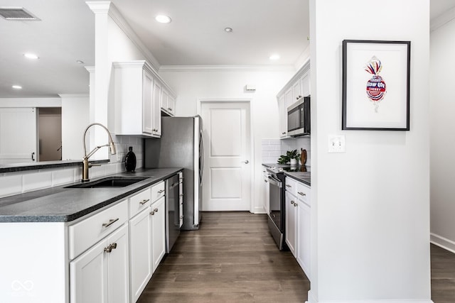 435 Virginia Ave Unit 106, Indianapolis, IN 46203 - kitchen featuring appliances with stainless steel finishes, a sink, dark countertops, decorative backsplash, and ornamental molding