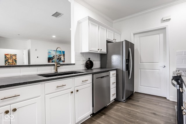 435 Virginia Ave Unit 106, Indianapolis, IN 46203 - kitchen featuring stainless steel appliances, a sink, crown molding, dark countertops, and white cabinets