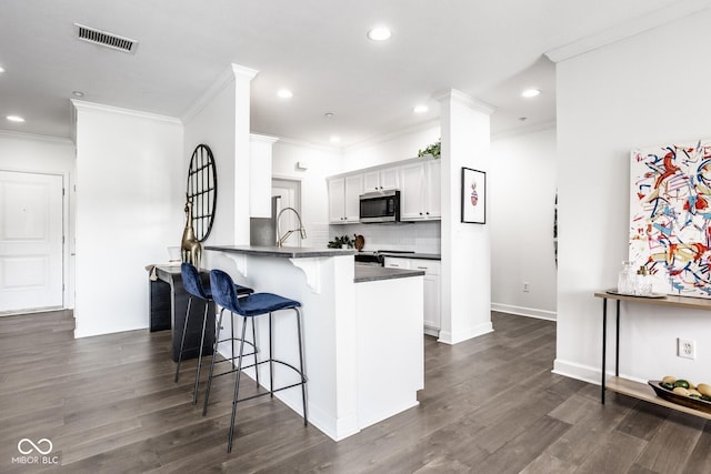 435 Virginia Ave Unit 106, Indianapolis, IN 46203 - kitchen featuring stainless steel microwave, dark countertops, a breakfast bar, recessed lighting, and a peninsula