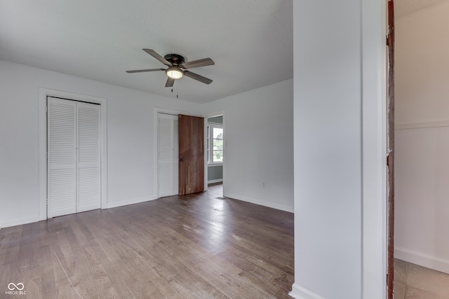 1601 Southern Ave, Beech Grove, IN 46107 - unfurnished bedroom featuring two closets, wood finished floors, baseboards, and a ceiling fan
