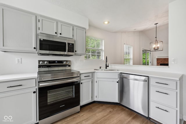 7061 Woodgate Cir, Fishers, IN 46038 - kitchen featuring appliances with stainless steel finishes, a sink, a chandelier, vaulted ceiling, and light countertops