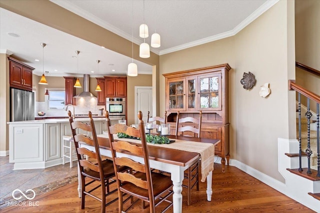 14711 Macduff Dr, Noblesville, IN 46062 - dining area featuring ornamental molding, light wood-type flooring, baseboards, and stairs