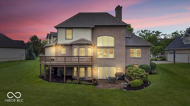 14711 Macduff Dr, Noblesville, IN 46062 - back of house at dusk with a chimney, a lawn, and brick siding