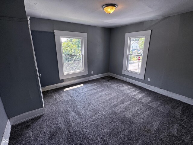 3502 N Kenwood Ave, Indianapolis, IN 46208 - empty room with healthy amount of natural light, dark colored carpet, and baseboards
