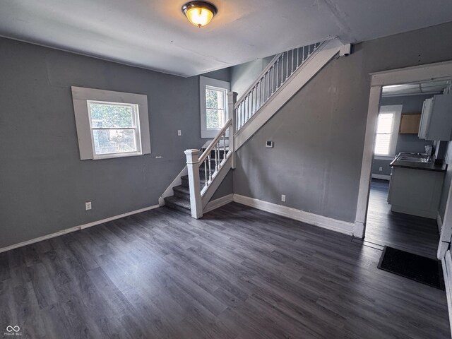 3502 N Kenwood Ave, Indianapolis, IN 46208 - unfurnished living room with stairs, dark wood-style floors, and baseboards