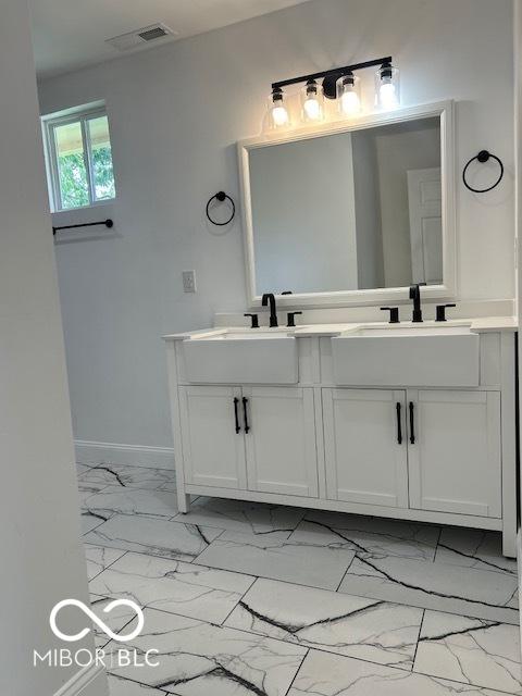 2936 Guilford Ave, Indianapolis, IN 46205 - bathroom featuring double vanity, marble look tile flooring, and baseboards