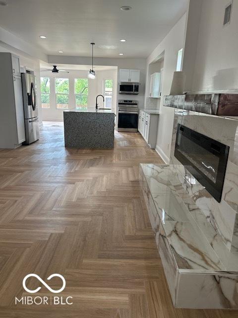 2936 Guilford Ave, Indianapolis, IN 46205 - kitchen with appliances with stainless steel finishes, light countertops, a glass covered fireplace, a ceiling fan, and recessed lighting
