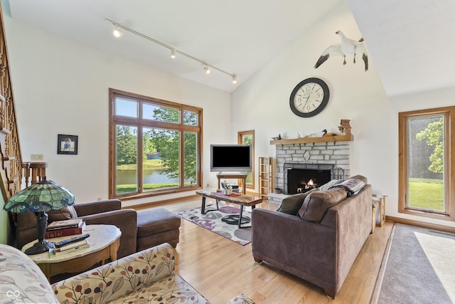 11875 W 700 S, Columbus, IN 47201 - living room with rail lighting, a warm lit fireplace, a towering ceiling, healthy amount of natural light, and light wood finished floors