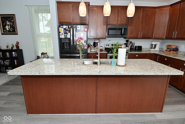 2330 Oak Dr, Clayton, IN 46118 - kitchen featuring stainless steel appliances, a center island with sink, pendant lighting, light wood-style floors, and light stone counters