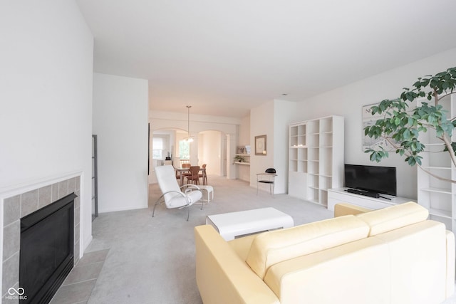 9117 Thoreau Ct, Fishers, IN 46037 - living area with arched walkways, light colored carpet, and a tile fireplace