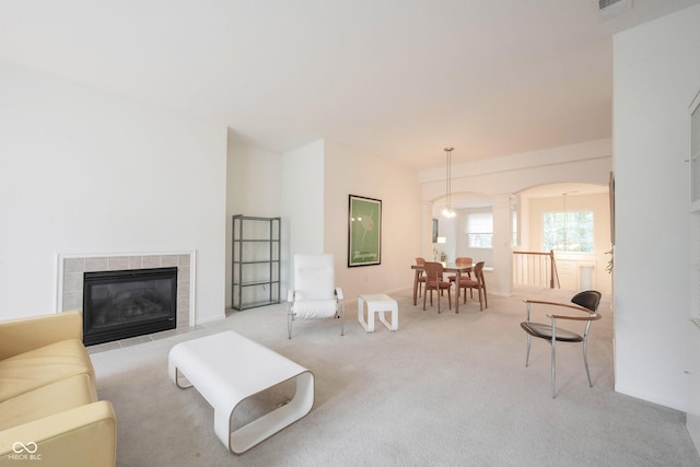 9117 Thoreau Ct, Fishers, IN 46037 - living room with decorative columns, arched walkways, carpet flooring, and a tiled fireplace
