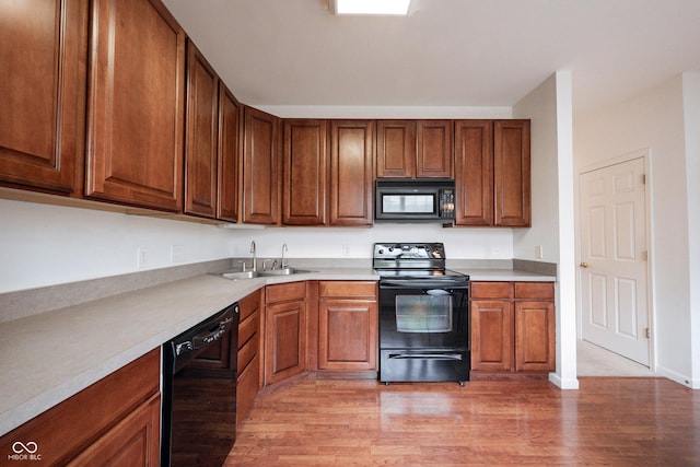 9117 Thoreau Ct, Fishers, IN 46037 - kitchen with black appliances, a sink, light wood finished floors, light countertops, and brown cabinets
