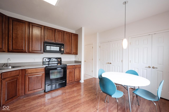 9117 Thoreau Ct, Fishers, IN 46037 - kitchen with black appliances, a sink, light wood-style flooring, light countertops, and hanging light fixtures