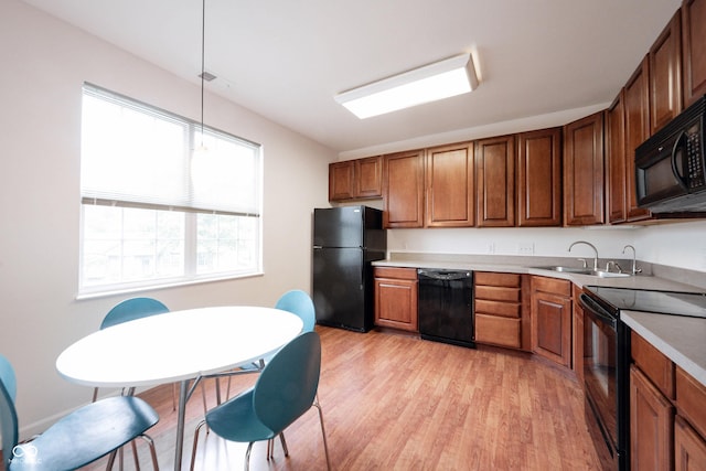 9117 Thoreau Ct, Fishers, IN 46037 - kitchen with black appliances, a sink, light wood-style flooring, decorative light fixtures, and light countertops