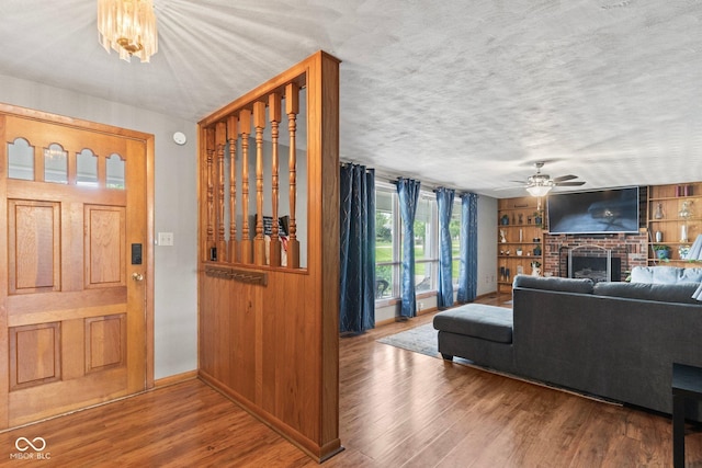 2137 W Bobwhite Dr, Scottsburg, IN 47170 - entryway with baseboards, wood finished floors, a brick fireplace, a ceiling fan, and a textured ceiling