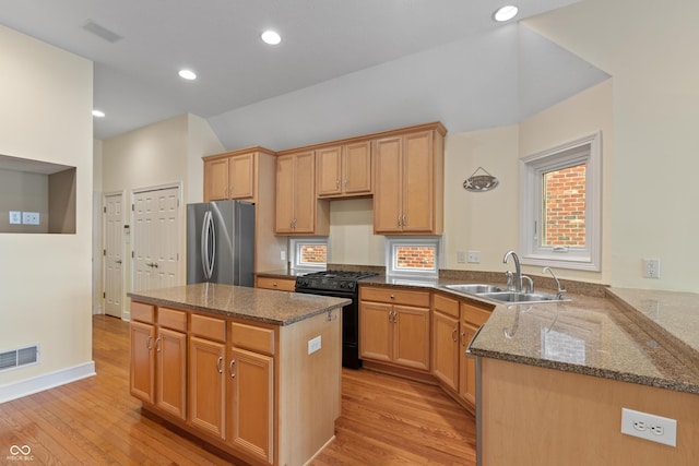 11065 Spice Ln, Fishers, IN 46037 - kitchen featuring black range with gas cooktop, freestanding refrigerator, light wood finished floors, dark stone countertops, and a kitchen island