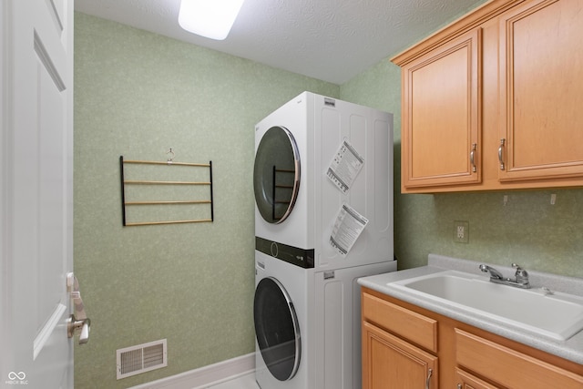 11065 Spice Ln, Fishers, IN 46037 - laundry area featuring estacked washer and dryer, cabinet space, and a textured ceiling