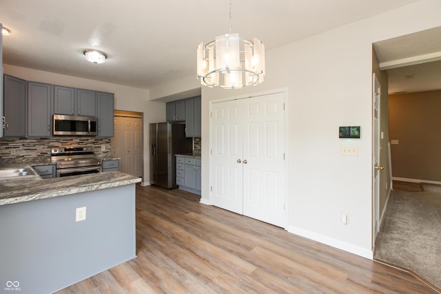 3623 Carroll Farms Dr, Indianapolis, IN 46235 - kitchen with appliances with stainless steel finishes, gray cabinets, a chandelier, and decorative backsplash