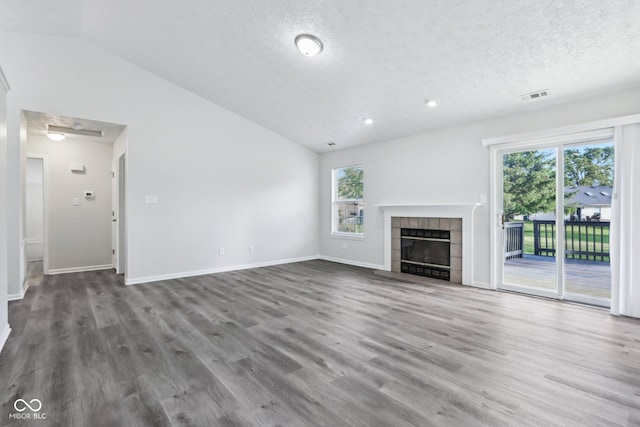 12250 Longstraw Dr, Indianapolis, IN 46236 - unfurnished living room featuring vaulted ceiling, healthy amount of natural light, a tiled fireplace, a textured ceiling, and wood finished floors