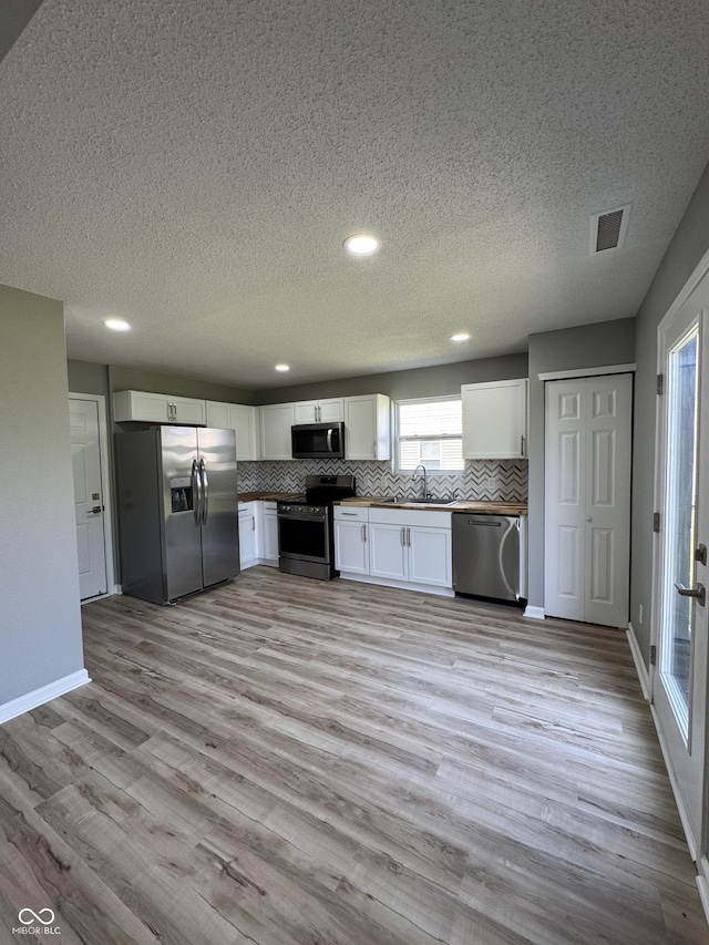 3327 Brandenburg Blvd, Indianapolis, IN 46239 - kitchen with stainless steel appliances, a sink, tasteful backsplash, white cabinets, and a textured ceiling
