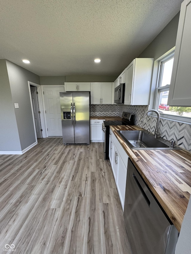 3327 Brandenburg Blvd, Indianapolis, IN 46239 - kitchen with stainless steel appliances, wood counters, a sink, a textured ceiling, and decorative backsplash
