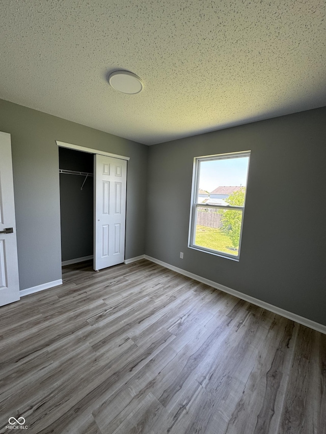 3327 Brandenburg Blvd, Indianapolis, IN 46239 - unfurnished bedroom with wood finished floors, a closet, baseboards, and a textured ceiling