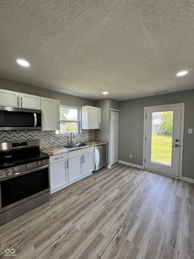 3327 Brandenburg Blvd, Indianapolis, IN 46239 - kitchen with appliances with stainless steel finishes, wooden counters, a sink, white cabinets, and a textured ceiling