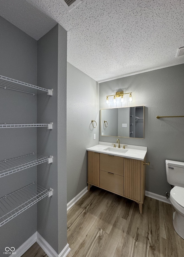 3327 Brandenburg Blvd, Indianapolis, IN 46239 - bathroom featuring wood finished floors, toilet, vanity, baseboards, and a textured ceiling