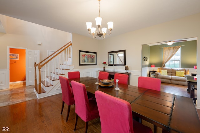 13271 Aquamarine Dr, Carmel, IN 46033 - dining area featuring a chandelier, stairway, wainscoting, wood finished floors, and a decorative wall