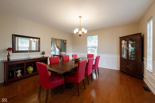 13271 Aquamarine Dr, Carmel, IN 46033 - dining space featuring a chandelier, dark wood-style flooring, plenty of natural light, a wainscoted wall, and a decorative wall