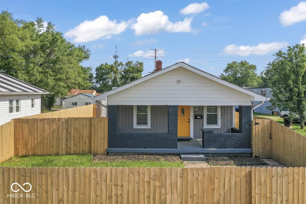 3716 W 16th St, Indianapolis, IN 46222 - bungalow-style house with a porch, a fenced front yard, a chimney, and brick siding