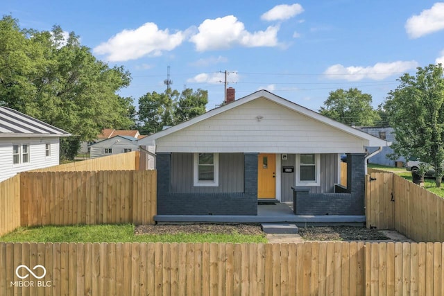 3716 W 16th St, Indianapolis, IN 46222 - bungalow-style house with a porch, a fenced front yard, a chimney, and brick siding