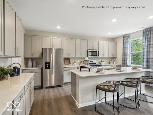 6049 Madera Dr, Whitestown, IN 46075 - kitchen featuring stainless steel appliances, light countertops, dark wood-style flooring, a kitchen bar, and recessed lighting