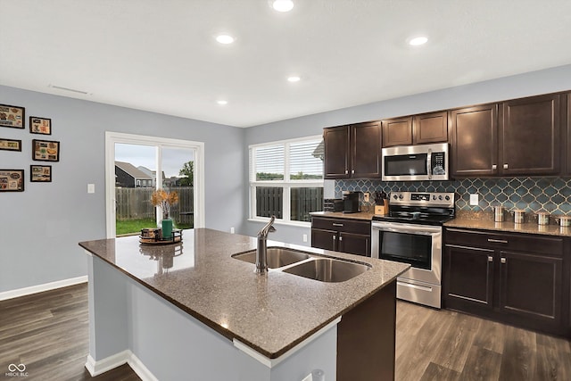 6645 Honeysuckle Way, Pendleton, IN 46064 - kitchen with stainless steel appliances, a sink, dark wood-style floors, dark stone counters, and decorative backsplash