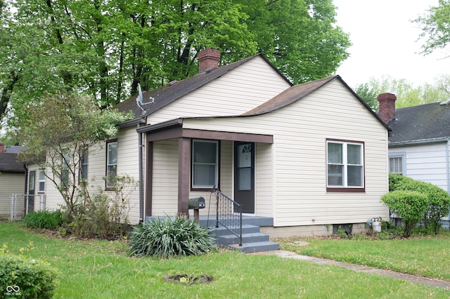 1331 N Berwick Ave, Indianapolis, IN 46222 - bungalow featuring a front yard, a shingled roof, and a chimney