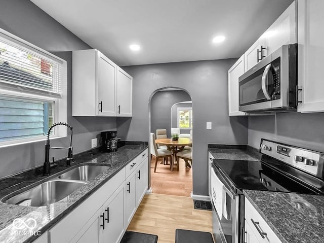 1331 N Berwick Ave, Indianapolis, IN 46222 - kitchen with stainless steel appliances, arched walkways, light wood-style flooring, white cabinetry, and recessed lighting