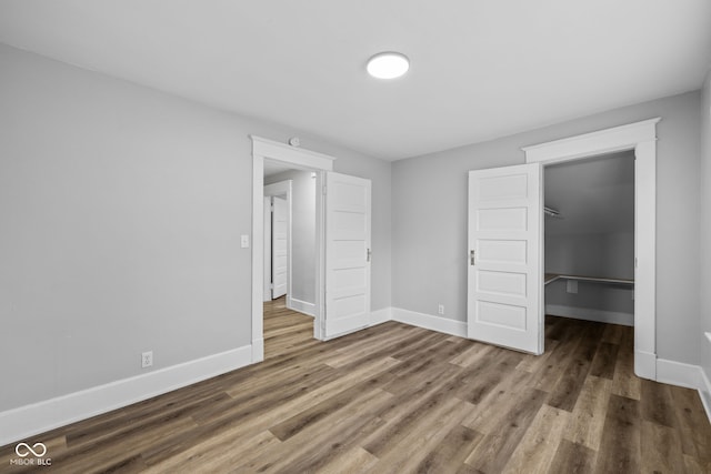 3227 Guilford Ave, Indianapolis, IN 46205 - unfurnished bedroom with baseboards, wood finished floors, a walk in closet, and a closet