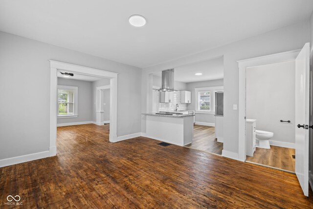 3227 Guilford Ave, Indianapolis, IN 46205 - unfurnished living room featuring a sink, baseboards, healthy amount of natural light, and dark wood-style flooring