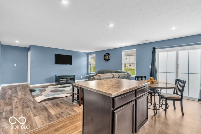 123 Campus Ln, Greenwood, IN 46143 - kitchen with light wood-type flooring, a kitchen island, dark brown cabinets, baseboards, and recessed lighting