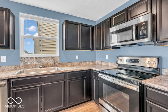 123 Campus Ln, Greenwood, IN 46143 - kitchen featuring appliances with stainless steel finishes, a sink, light countertops, light wood-type flooring, and dark brown cabinets